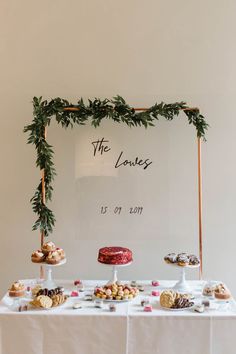 a table topped with cakes and pastries under a sign