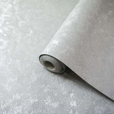 a roll of silver metallic foil on top of a white table cloth with a black edge