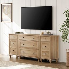 a large flat screen tv mounted to the side of a wooden dresser in a living room