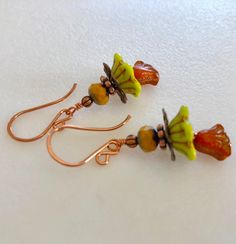 "Adorable new Czech glass premium flower earrings in chartreuse green and orange opaline with mustard yellow and copper accents. Opaque chartreuse Czech glass bellflowers with copper Picasso finish are accented with little Czech glass lilies in burnt orange opaline with metallic copper wash and mustard yellow Picasso rondelles. Wire wrapped in bright copper with copper accents. Ear wires are handmade German copper. Total drop is 1 3/4\"." Green Hypoallergenic Flower-shaped Earrings, Hypoallergenic Green Flower-shaped Earrings, Nickel-free Yellow Czech Glass Earrings, Nickel Free Yellow Czech Glass Earrings, Orange Flower-shaped Adjustable Earrings, Adjustable Nickel-free Yellow Flower Earrings, Yellow Czech Glass Earrings For Gifts, Nickel-free Orange Flower Earrings, Hypoallergenic Green Flower Earrings