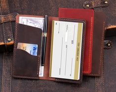 a brown leather wallet with a checkbook, pen and credit card in the pocket