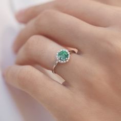 Even the legendary Queen Cleopatra ornamented herself with Emerald. Emerald jewels are traditional presents for 20th and 35th wedding anniversaries, but magical green beauty is great engagement piece too. This ring is crafted at our atelier in white gold with a halo of diamonds. #klenota #klenotajewelry #whitegold #14k #14carat #symboloflove #finejewelry #specialoccasion #jewelrymakers #klenotaring #ring #diamond #emerald #haloring #gemstonering #engagement #anniversarygift Dazzling Emerald Ring With Halo Setting For Promise, Luxury Round Diamond Emerald Ring With Halo Setting, Formal Emerald Ring With Halo, Formal Round Emerald Ring With Halo, Formal Emerald Ring With Halo And Round Cut, Round Emerald Ring With Diamond Halo Setting, Formal Emerald Halo Ring With Round Cut, Fine Jewelry Emerald Ring In White Gold With Halo, Emerald Ring With Halo Setting In Fine Jewelry Style