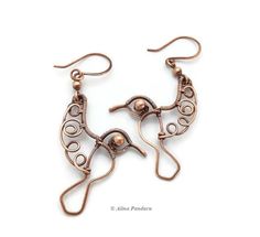 two pairs of copper toned metal earrings with swirls and circles in the shape of birds