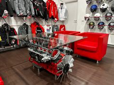 a red couch sitting next to a glass table in a room filled with sports gear