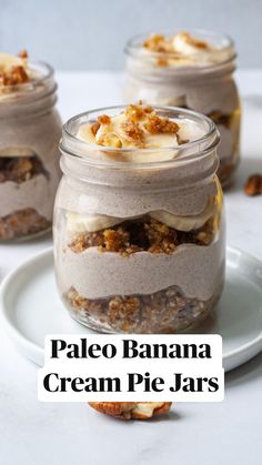 three jars filled with dessert sitting on top of a white plate next to a spoon