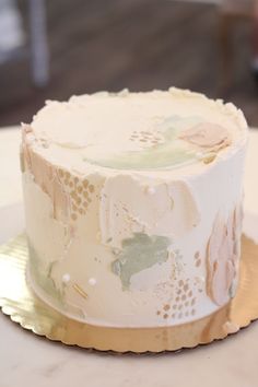 a white cake sitting on top of a table covered in frosting and gold foil