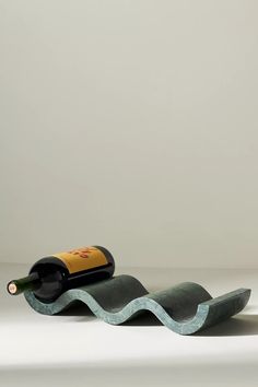 a bottle of wine sitting on top of a wave shaped object