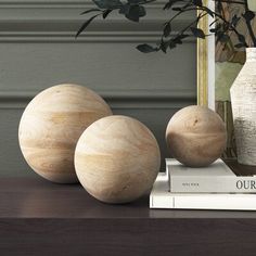 three wooden balls sitting on top of a table next to a vase and bookcase