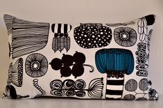 a black and white pillow with blue flowers on the front is sitting on a table