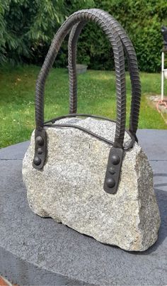 a handbag made out of rocks sitting on top of a cement slab