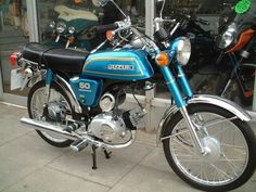 a blue and black motorcycle parked in front of a store window with other motorcycles behind it