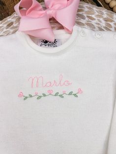 a baby sweater with a pink bow on the front and name made written in cursive writing