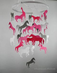 a group of horses that are hanging from a chandelier with pink and grey silhouettes