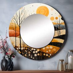 a round mirror sitting on top of a wooden table next to a vase with flowers