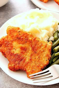 a white plate topped with fried chicken, mashed potatoes and green beans