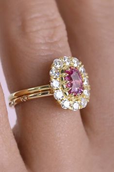 A symphony of sparkle shines brightly from this oh so easy to wear low-profile ring. At its center sits a glowing vivid natural and untreated pink sapphire. Sculpted around the sapphires exact portions by Jacob, bands can sit flush on either side. This ring is perfect as an engagement ring or part of a fun party stack. Divine and bright single antique cut diamonds surround adding a unique old-world charm. Classic Pink Diamond Cluster Ring, Formal Pink Sapphire Rings With Cushion Cut, Formal Pink Sapphire Cushion Cut Rings, Luxury Pink Diamond Ring With Halo Design, Classic Pink Cluster Ring With Center Stone, Pink Cluster Ring With Brilliant Cut, Luxury Pink Halo Diamond Ring, Dazzling Pink Sapphire Rings With Brilliant Cut, Pink Brilliant Cut Cluster Ring