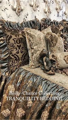 a bed covered in black and gold comforter next to a headboard with ornate pillows