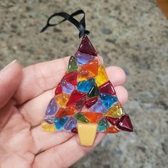 a hand holding a small glass christmas tree ornament