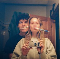 two people taking a selfie in front of a mirror with toothbrushes sticking out of their mouths