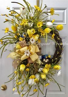 a wreath with yellow and white flowers on the front door