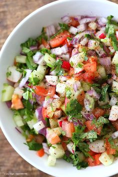 a white bowl filled with chopped vegetables on top of a wooden table