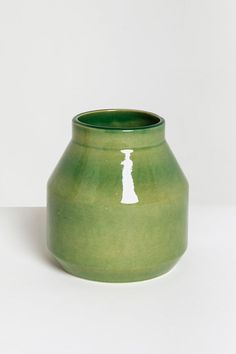 a green vase sitting on top of a white table