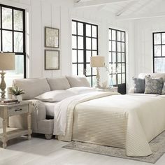 a living room filled with furniture and windows next to a white floor covered in pillows