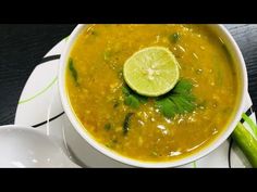 a white bowl filled with soup on top of a plate next to a green spoon