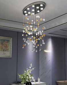 a chandelier hanging from the ceiling in a room with grey walls and white furniture