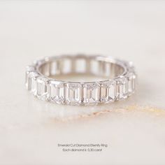 an emerald cut diamond band ring on a white surface