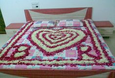 a heart shaped bed with pink and white flowers on the bedspread is shown