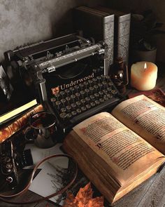 an old fashioned typewriter sitting on top of a table next to candles and books