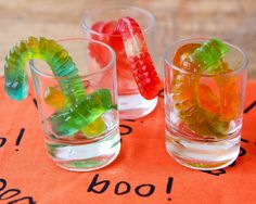 three glasses filled with gummy bears sitting on top of a table