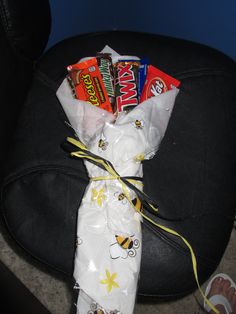 candy bar wrapped in plastic sitting on top of a black chair next to someone's feet