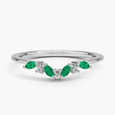 a white gold ring with three pear shaped emeralds and diamonds on the sides, set in