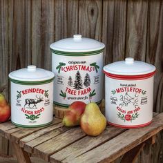 three canisters with apples and pears on a wooden table