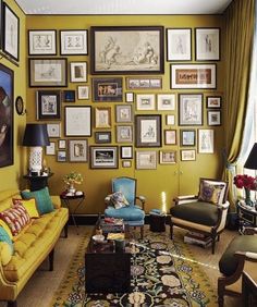 a living room filled with yellow furniture and pictures on the wall above it's coffee table