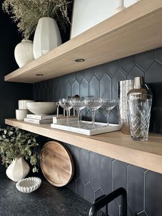 the shelves in this kitchen are filled with dishes and vases, including wine glasses