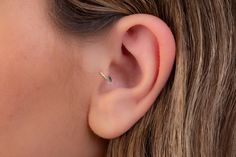 a close up of a woman's ear with a single diamond in the middle