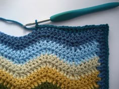 a crocheted square is shown with a knitting needle