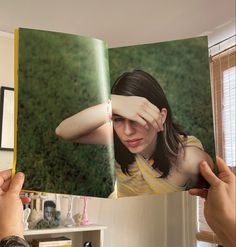 two hands holding an open photo book with a woman covering her eyes