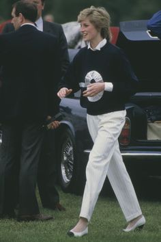 the woman is walking with her hand in her pocket while wearing white pants and heels