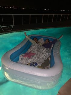 two people laying on an inflatable raft at the edge of a swimming pool