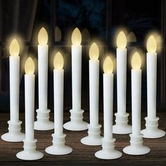 a group of white candles sitting on top of a wooden table next to each other