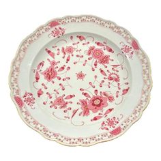 a pink and white plate with flowers on it's rim, sitting in front of a white background