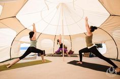 two women are doing yoga in a tent