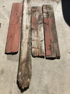 three pieces of wood sitting on top of a cement ground next to a wooden pole