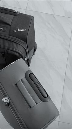 two pieces of luggage sitting next to each other on top of a tile floor with the words go home written on it