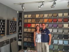 a man and woman standing next to each other in front of a display of paint samples