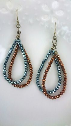 two pairs of beaded tear earrings on a white surface with bubbles in the background